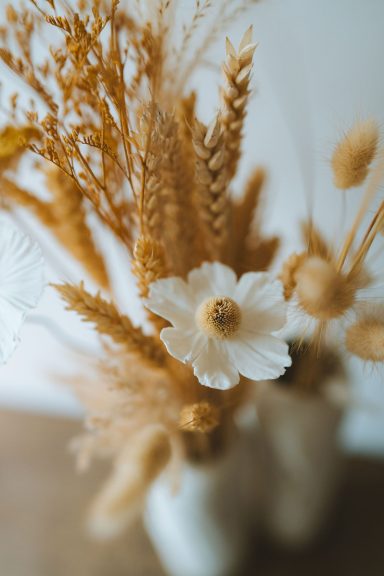 Arrangement de fleurs séchées beige et blanche dans un vase.