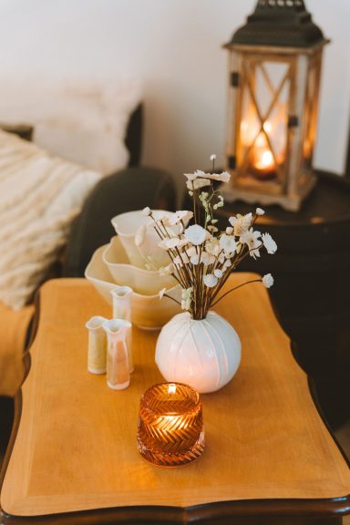 Décor de table avec vase, bougie, fleurs séchées et lanterne chaleureuse.